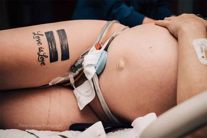 A pregnant woman laying on her side with the tattoo reading love is love