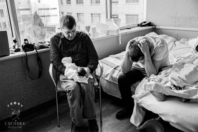 Two men in a hospital room, the older man holding a still born baby