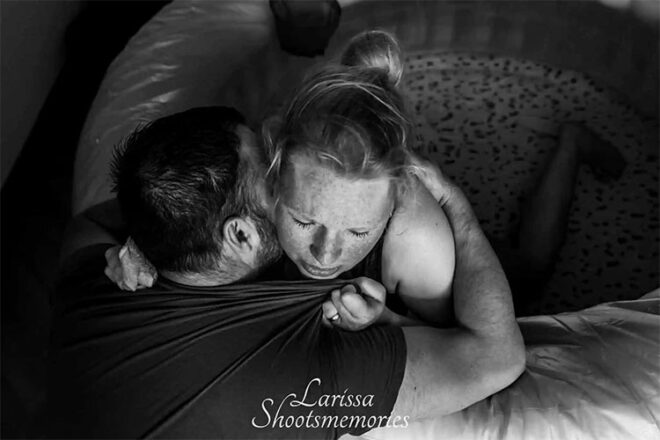 A man and a woman embracing while she is in labour in a paddle pool