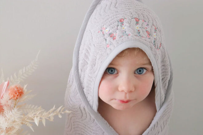 A toddler wearing the Botanical Personalised Baby Hooded Towels from Milkmaid Mumma