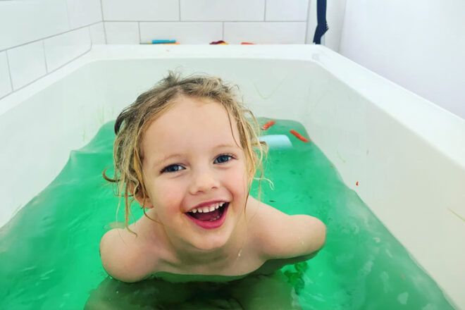 A child in a bath with the Nourish by Nature Bath Colour Rocks