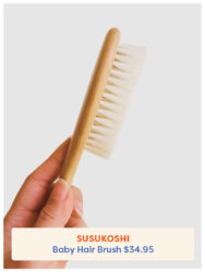A hand holding the Susukoshi Hair Brush