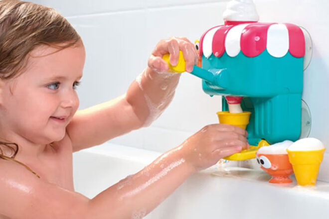 A child playing with the Tomy Toomies Deluxe Foam Cone Factory in the bath