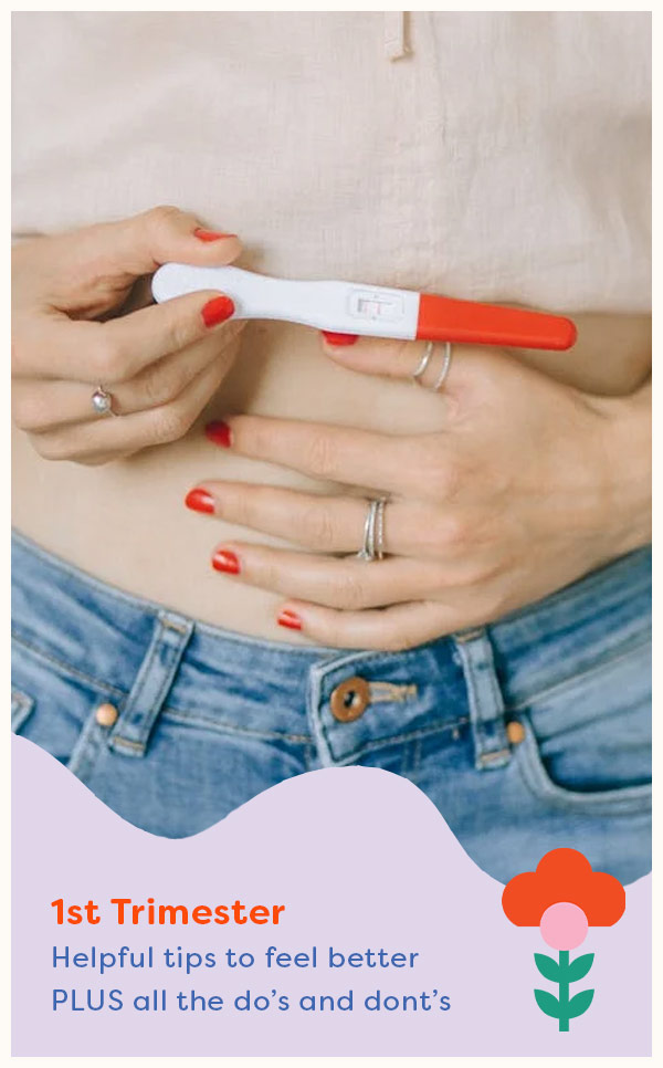 woman holding a positive pregnancy test in front of her bare belly