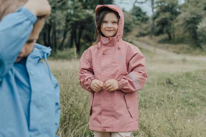 A young girl wearing a Crywolf Magic Jacket Raincoat standing outdoors