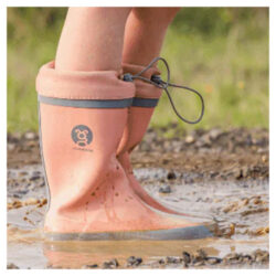 A child playing in the mud wearing Grubbybub Kids Gumboots in Just Peachy