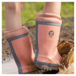 A child playing in the mud wearing Grubbybub Kids Gumboots in Just Peachy