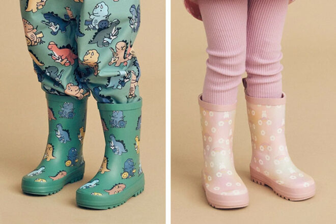 Two young kids wearing Huxbaby Rainboots in the designs Dino Band and Rainbow Bunny