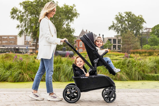 A mother walking with her children in the Jiffle Wagon 6-in-1 Strollers in the Duo configuration in the colour black