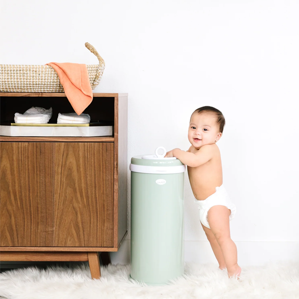 Baby standing next to an Ubbi Nappy Pail in Sage