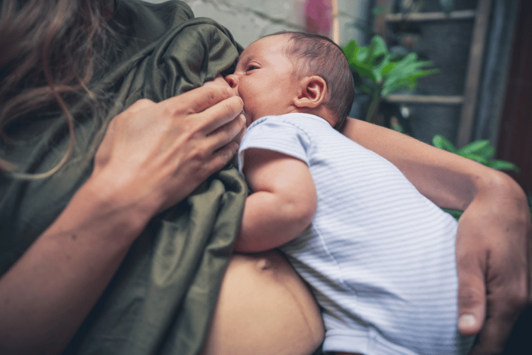 Exhausted mother breastfeeding her newborn in the early weeks of learning to nurse