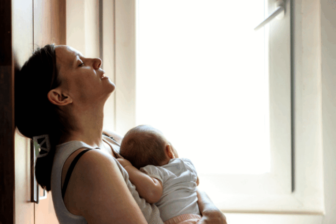 Exhausted new mother holding her newborn after breastfeeding in the first weeks