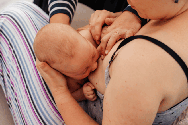 Lactation consultant supporting a new mother with breastfeeding in the early weeks